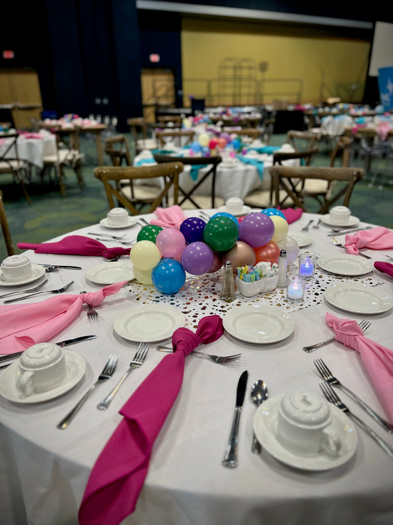 Banquet tables set with pastel balloon centerpieces