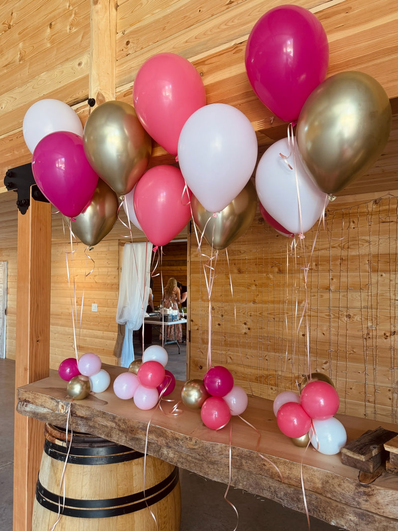 Pink white and gold helium centerpiece on a barrel table