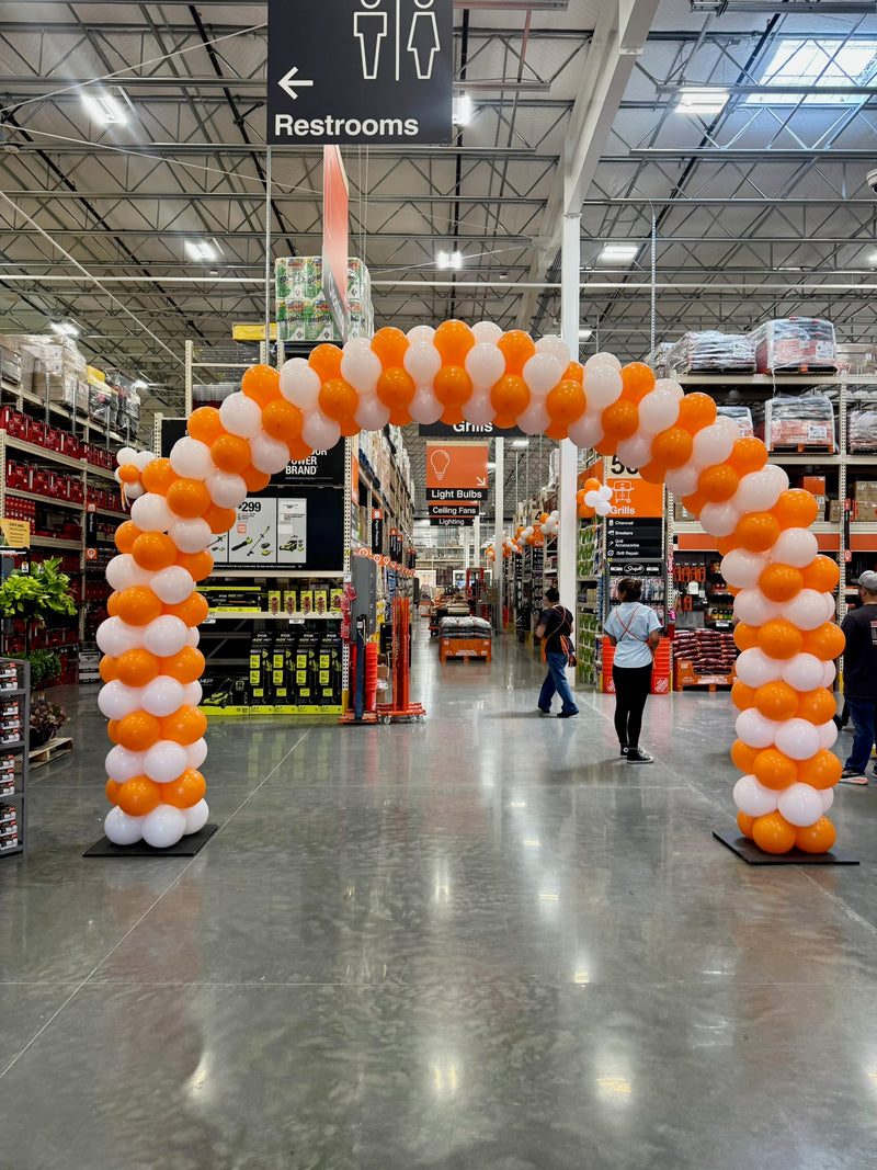 Orange and white balloon arch over a Home Depot aisle entrance
