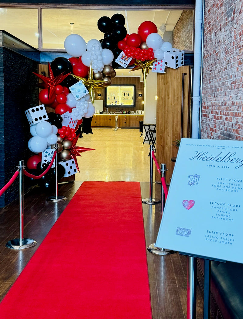 Red black and white casino themed balloon garland over a red carpet