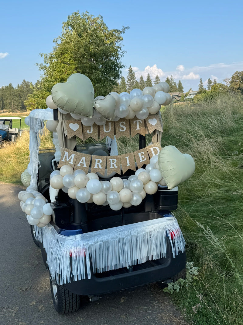 Just Married golf cart decorated with ivory balloons and fringe
