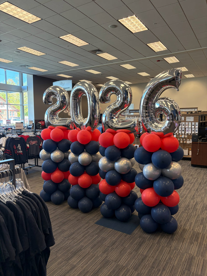 Silver 2026 graduation numbers on navy and red balloon columns
