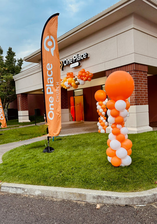 Orange and white spiral balloon columns at a storefront
