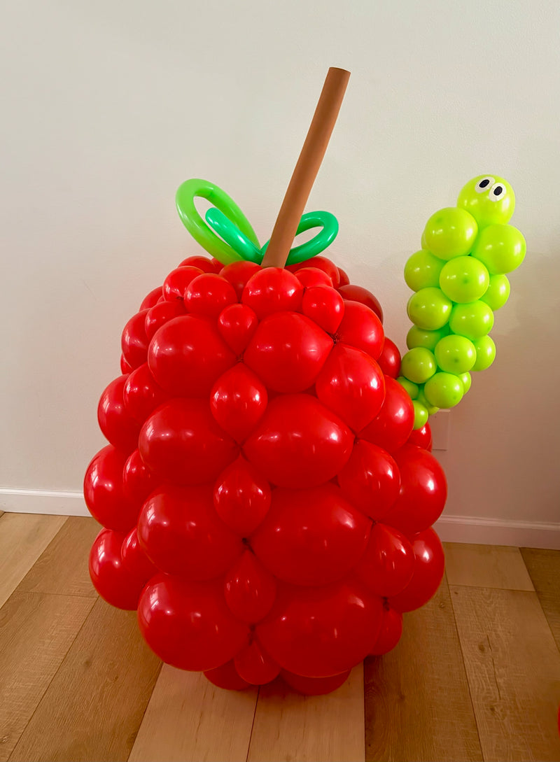 Giant apple balloon sculpture with caterpillar
