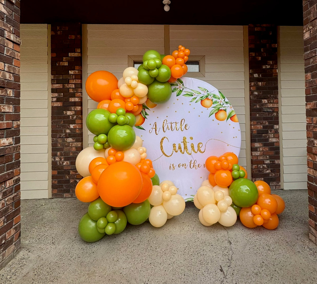 A Little Cutie citrus themed arch panel with orange and green garland